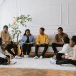 Grupo de jovens reunidos em casa, lendo a Bíblia e compartilhando experiências de fé em comunidade cristã