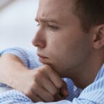 Homem jovem com ansiedade chorando sozinho precisando entregar preocupações a Deus