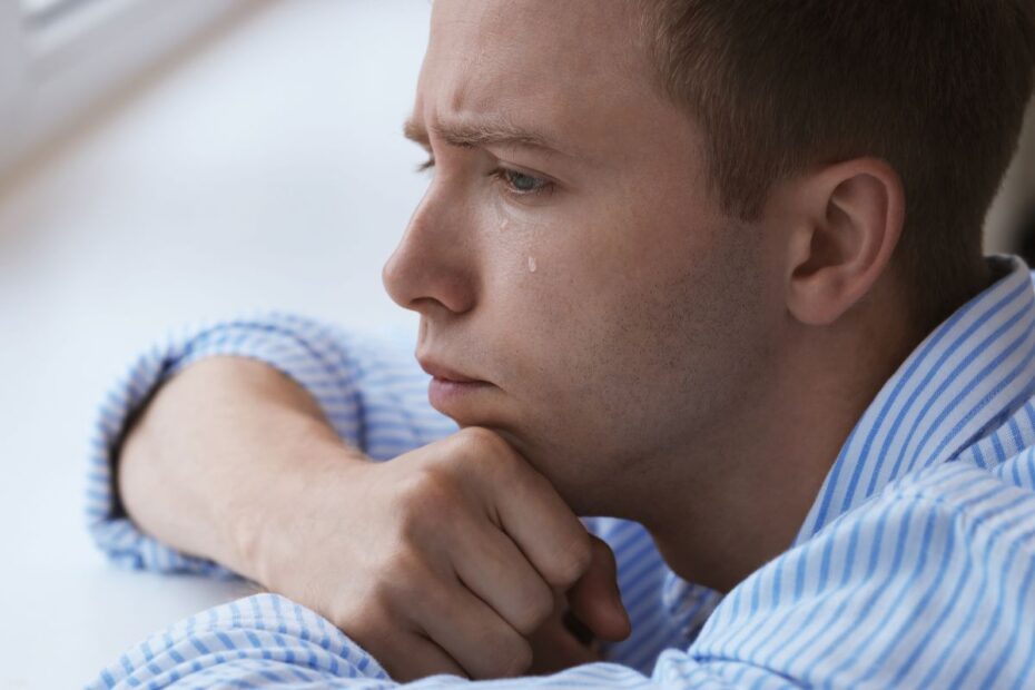 Homem jovem com ansiedade chorando sozinho precisando entregar preocupações a Deus